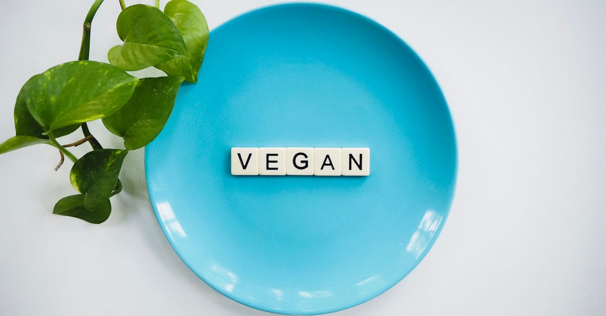 A blue plate with the word 'VEGAN' and a leafy plant, symbolizing a plant-based diet.